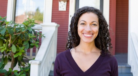 Young woman smiling in front of a house