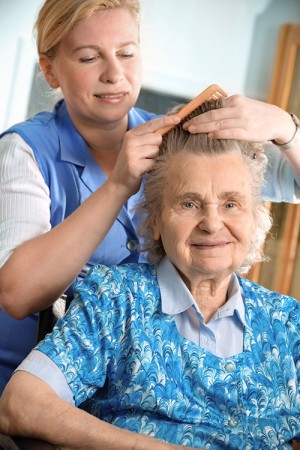 Elderly woman having her hair brushed by a Provider